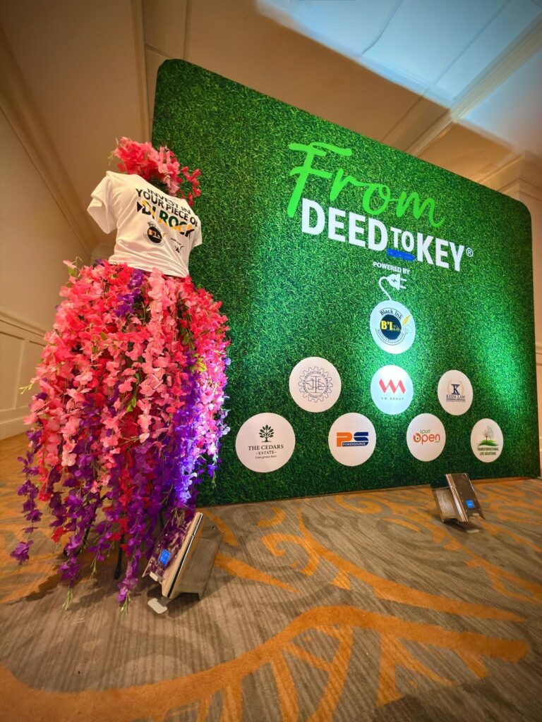 From Deed to Key event backdrop with floral arrangement