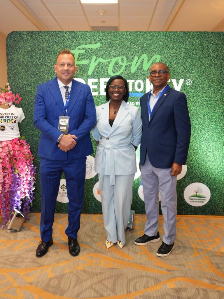 Three guests posing at the From Deed to Key backdrop